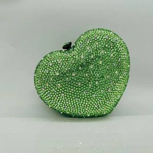 Macro shot of green emerald rhinestones and crystal clasp on heart-shaped clutch bag