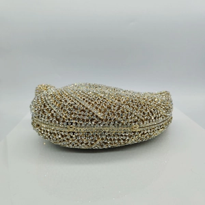 Macro detail of leaf-shaped evening clutch featuring dense crystal pave and gold metal frame
