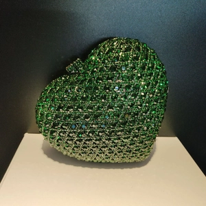 Macro shot of green rhinestone heart clutch bag with emerald crystals and metal clasp