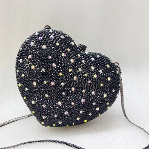 Detail of a heart-shaped evening bag with black rhinestones and a grey metal chain
