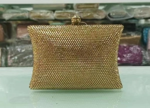 Detail of champagne gold rhinestone clutch bag featuring a decorative crystal top clasp