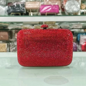 Close-up of luxury red rhinestone clutch bag with sparkling diamond ball clasp