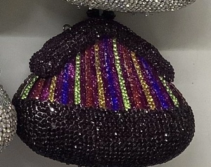 Close-up of a rhinestone evening bag with vertical rainbow stripes on a black base
