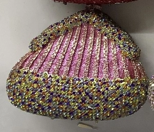 Detailed macro shot of shell-shaped evening bag with colorful rhinestones and pink stripes