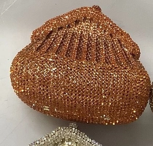 Close-up of pleated rhinestone evening clutch bag in orange bronze sparkling finish