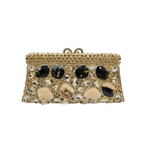 Dettaglio pochette da sera dorata con piccoli strass e grandi gemme multicolori incastonate