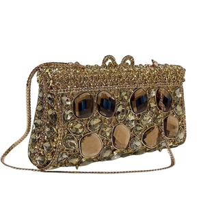 Dettaglio pochette da sera dorata con strass, gemme ambrate e chiusura a cuore