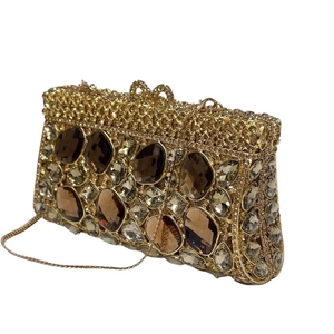 Dettaglio della pochette dorata con strass, grandi cristalli ambra e maglia metallica