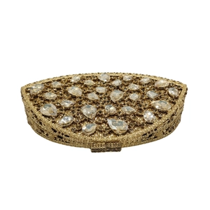 Detail of hollow metal design with oversized teardrop rhinestones on golden evening bag