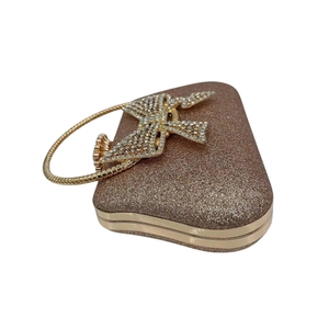 Detailed shot of rose gold glitter clutch featuring a sparkling rhinestone bow buckle