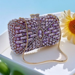 Detail of a purple rhinestone evening bag with gold metal frame and floral background