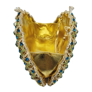 Detail of a luxury peacock heart clutch bag with blue gems and gold chain strap