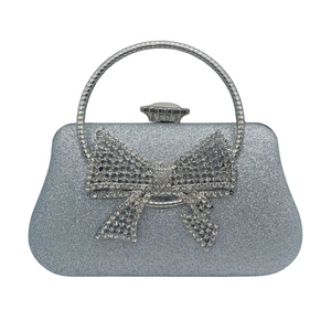 Detailed view of silver glitter evening clutch featuring a large rhinestone bow decoration