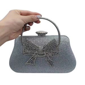 Detail of silver sequin evening clutch bag with a large rhinestone bow decoration