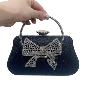 Macro detail of black glitter evening clutch featuring a sparkling rhinestone bow buckle