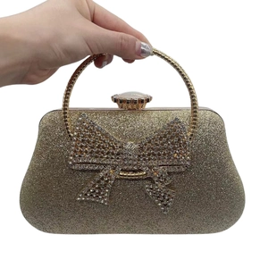 Macro detail of champagne glitter clutch bag with crystal bow and metallic handle
