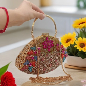 Detail of floral crystal clutch featuring pink rhinestones and a gold metal ring handle