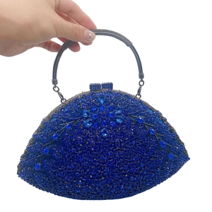 Detail of royal blue rhinestone clutch bag with metallic ring handle and floral design