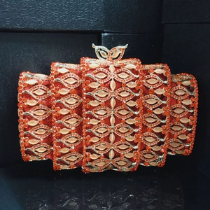 Macro shot of red crystal evening clutch with crown clasp and golden metal frame detail
