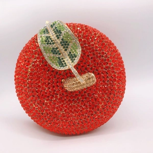 Detailed view of red apple clutch bag featuring sparkling rhinestones and golden leaf clasp