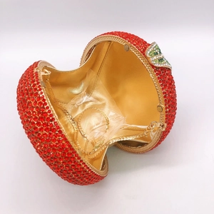 Detail of red apple rhinestone clutch bag showing gold interior and leaf-shaped clasp