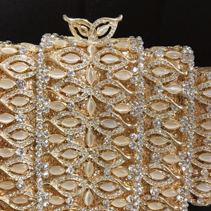 Detail of luxury gold evening clutch with rhinestones, cat-eye stones and butterfly clasp