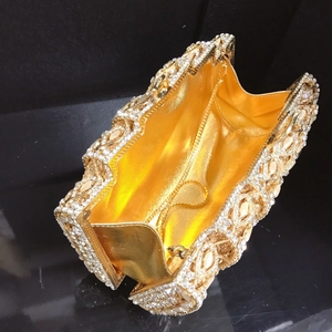 Detail of the golden evening clutch showing the rhinestone metal frame and inner lining
