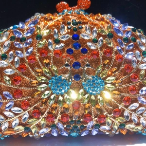 Gros plan de strass multicolores sur une pochette de soirée luxe motif paon doré