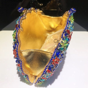 Gros plan d'une pochette paon avec strass multicolores et chaîne dorée