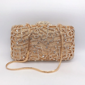 Detailed view of hollow musical note pattern and crystals on golden evening clutch