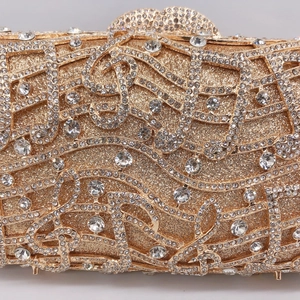 Macro view of crystal music note patterns and rhinestones on gold evening clutch bag