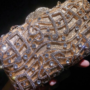 Detailed view of music note shaped evening bag with golden crystals and metal carvings