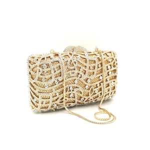 Close-up of golden music note clutch bag with sparkling rhinestones and metal chain