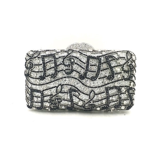 Detailed view of silver rhinestone clutch bag with black musical note crystal pattern
