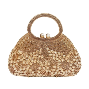 Detailed close-up of hollowed-out rhinestone evening bag with elegant pearl clasp and gold handle