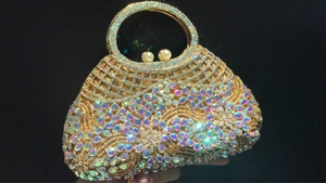 Detail of gold hollow metal frame with crystals and pearl closure on evening bag