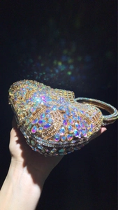 Detail of heart-shaped gold evening bag featuring colorful rhinestones and metal handle