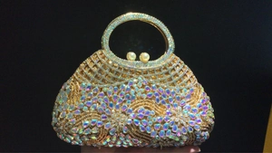 Close-up of luxury hollow evening bag with colorful rhinestones and pearl handle detail