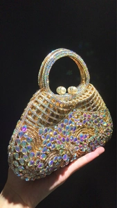 Detail view of a gold clutch bag with colorful rhinestones, wave patterns and pearl clasp