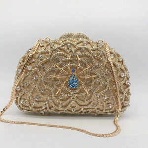 Detail of gold spider clutch bag with blue rhinestones and gold snake chain strap