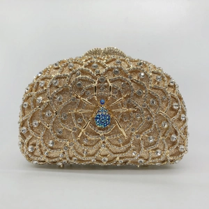 Detail of gold spider clutch bag featuring intricate blue crystal spider and rhinestone mesh