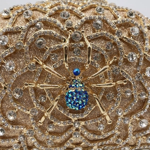 Detailed close-up of crystal-encrusted gold spider motif on a hollow-out evening clutch