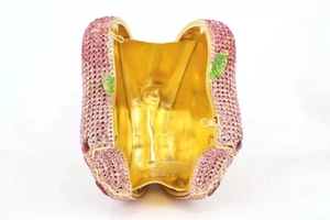 Detail of apple-shaped clutch bag showing pink rhinestones and golden metallic interior