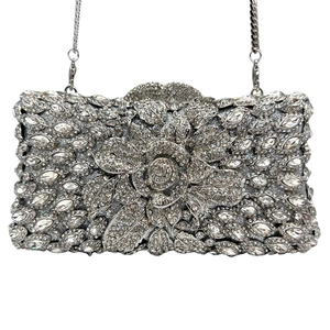 Dettaglio di una borsa da sera argentata con fiori di strass e tracolla a catena