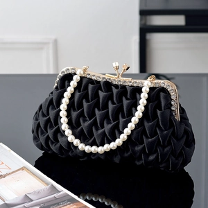 Detailed view of black pleated satin clutch with pearl handle and rhinestone clasp