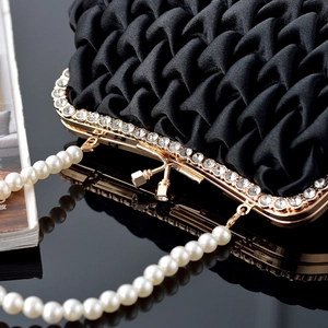 Detail of black satin pleated clutch with sparkling rhinestone edge and pearl handle chain