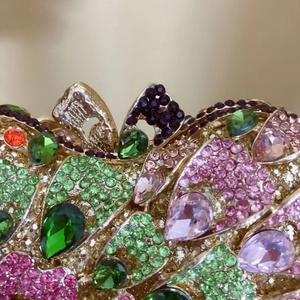 Macro detail of luxury evening bag featuring emerald crystals and colorful rhinestones