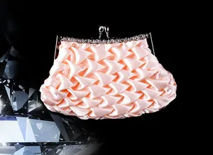 Detailed view of apricot satin clutch with pleated fabric and rhinestone metal frame