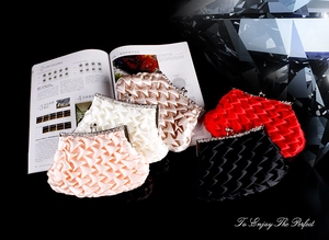 Detail of pleated satin clutches in five colors with rhinestone metal clasps