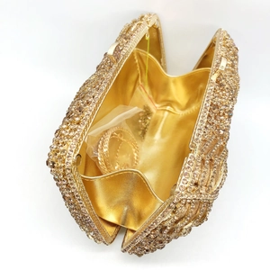 Macro shot of gold evening clutch showing rhinestone texture and golden satin lining interior